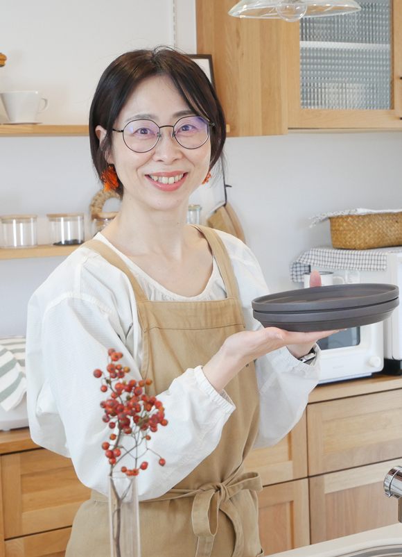 キッチンで器を持ついわたまきこ