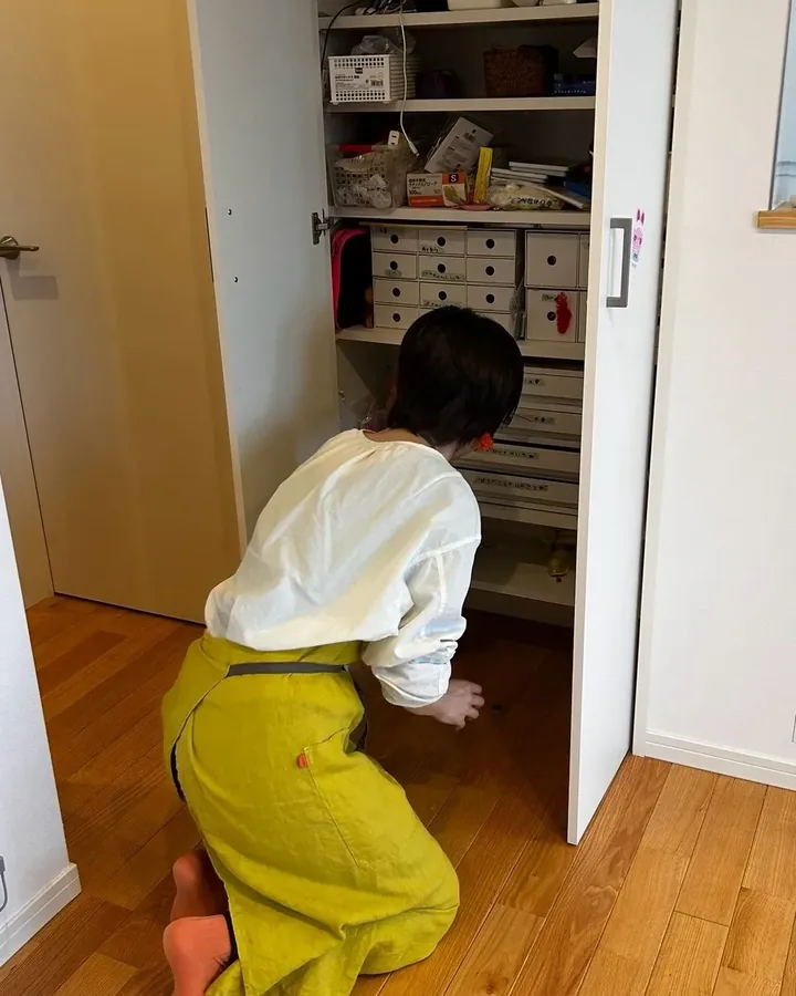 作業中。収納の前にしゃがんで収めているところ(後ろ姿)